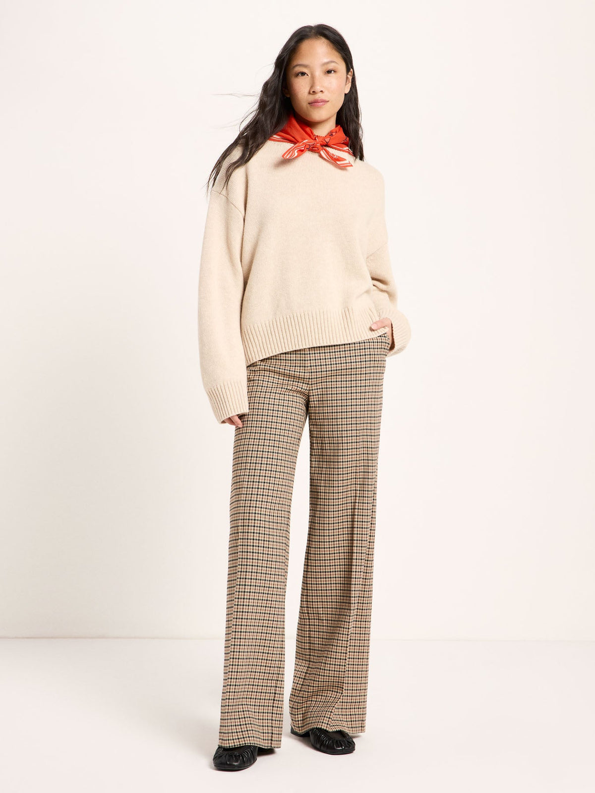 Pantalon Marlene à carreaux laine vierge et coton bio LANIUS Noir & beige – vue de face, avec une maille écrue et un foulard rouge