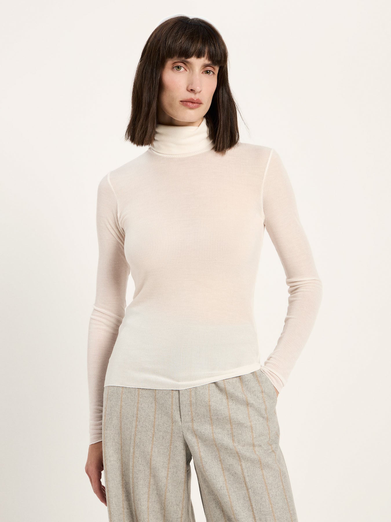 Top col roulé en fine côte LANIUS Crème porté avec un pantalon rayé gris – vue de face