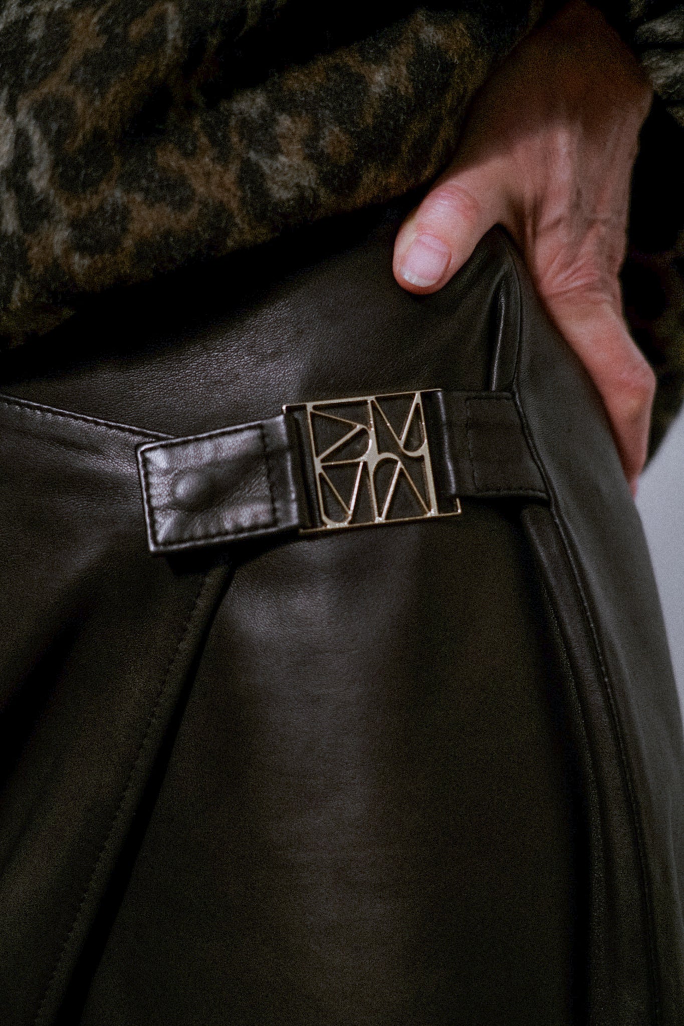 Jupe portefeuille en cuir MOS MOSH noire – détail de la boucle métallique sculptée à la hanche