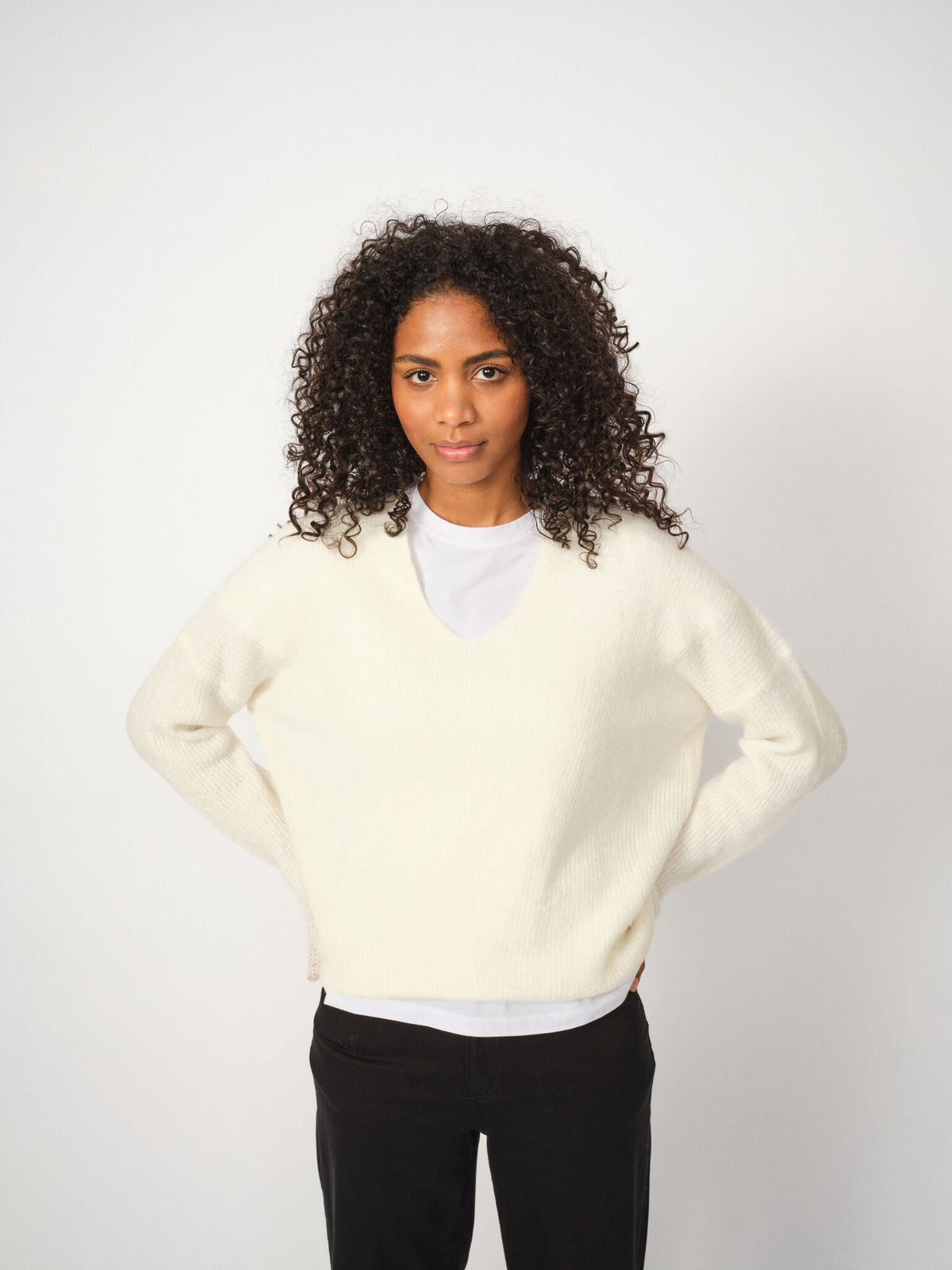 Pull col V en alpaga MOS MOSH écru porté sur un t-shirt blanc et un pantalon noir – vue de face