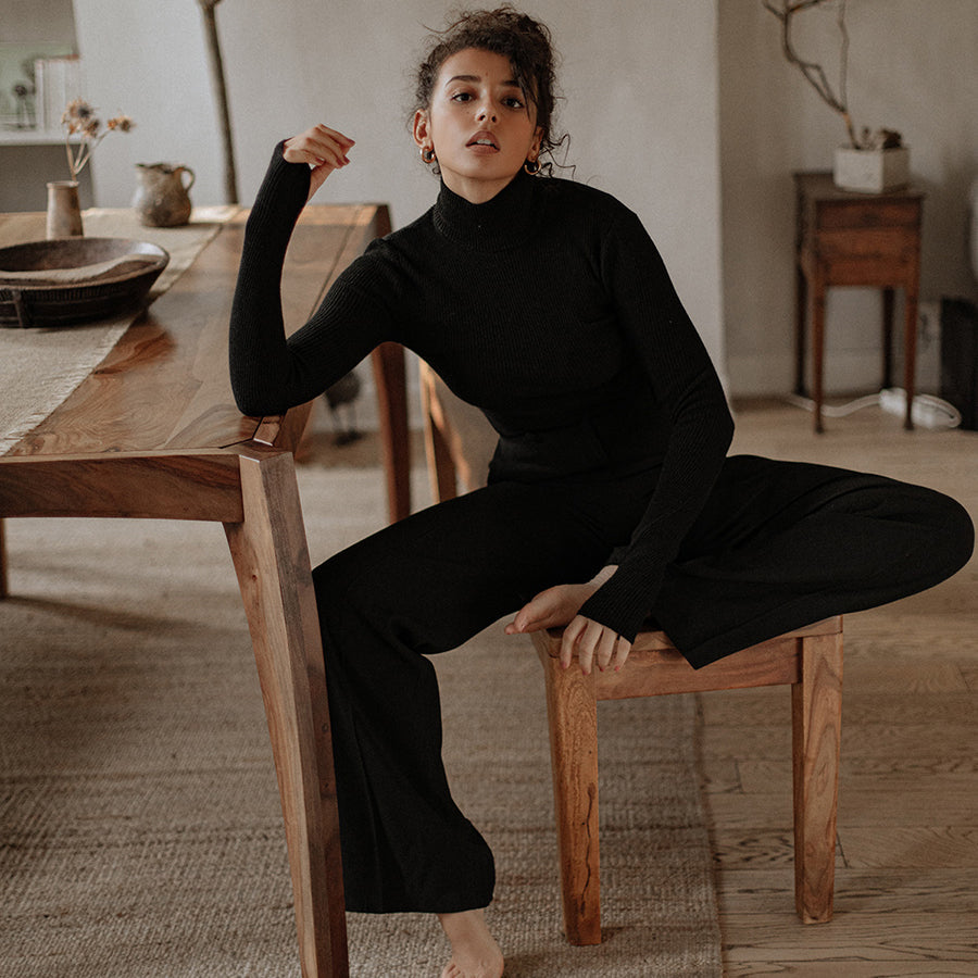 Col roulé fin Nuage Cashmere en noir, porté assise avec un pantalon noir