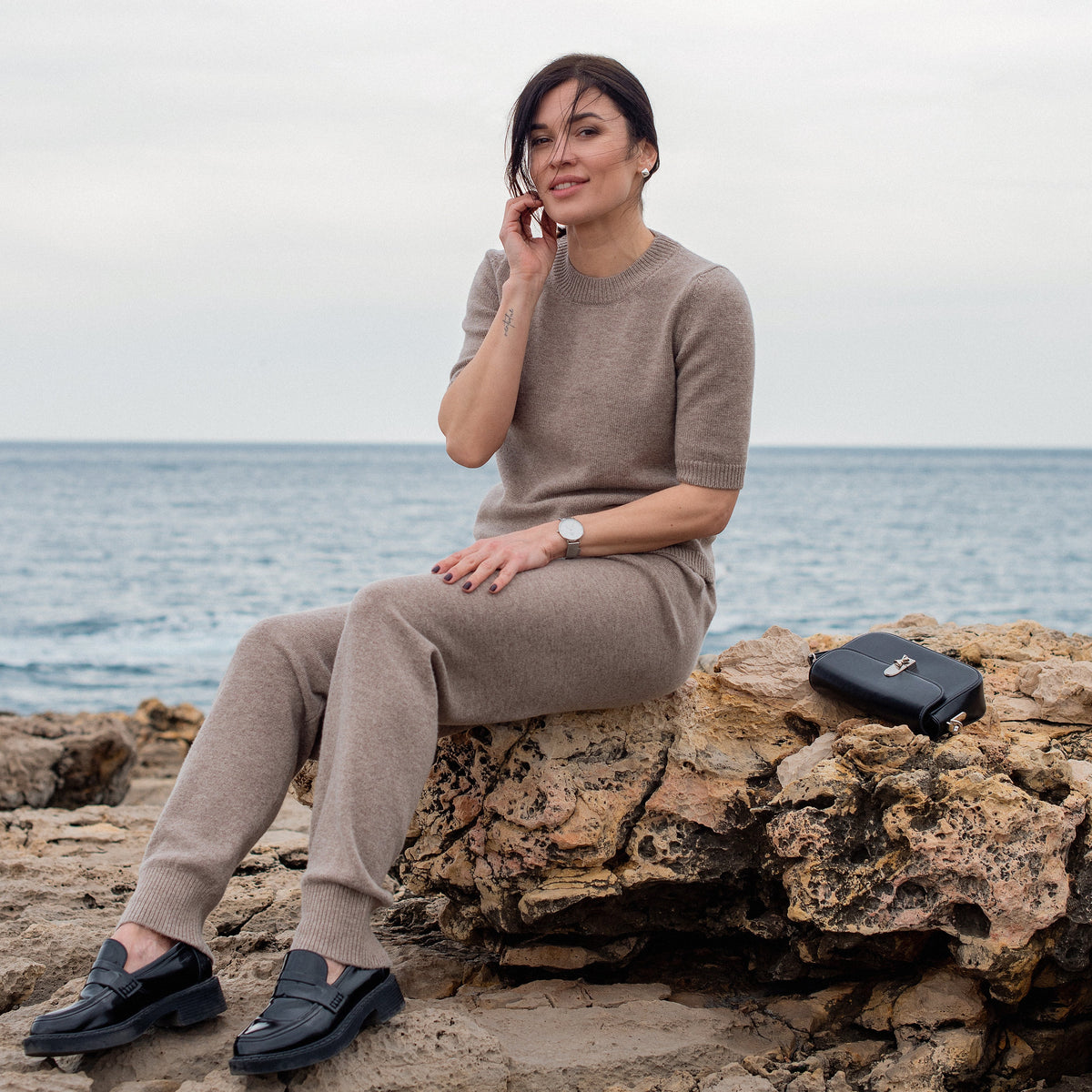 Jogging en cachemire Nuage Cashmere Cappuccino, porté assise au bord de la mer