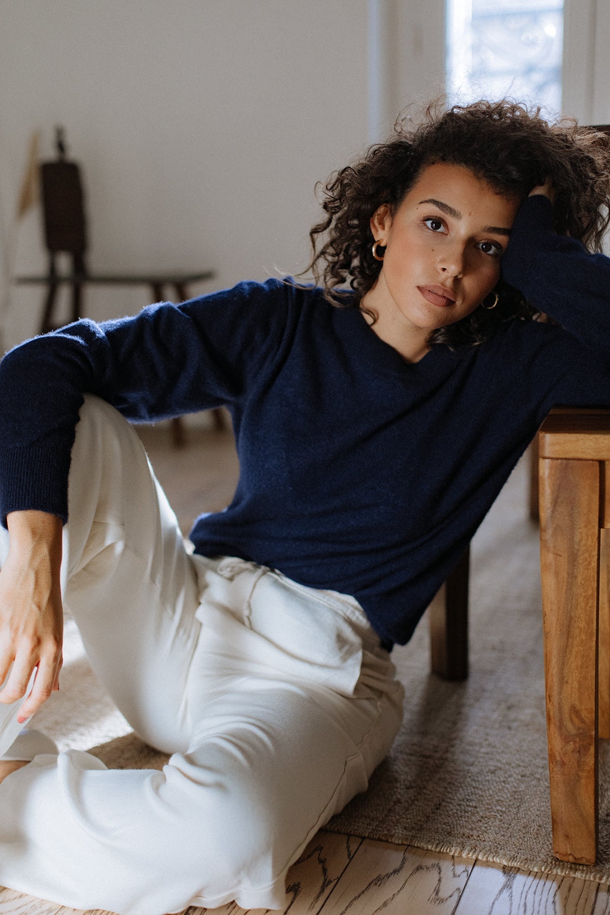 Pull col rond Nuage Cashmere en Indigo, porté assise avec un pantalon blanc