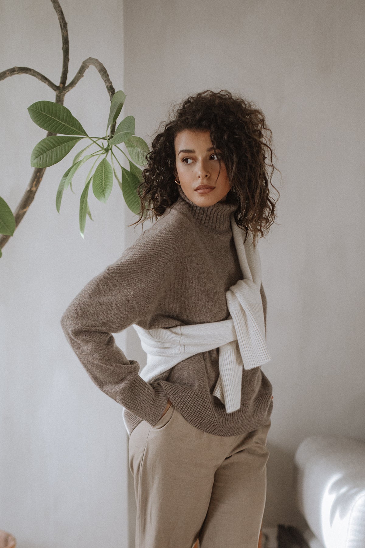 Pull col roulé Nuage Cashmere en Hot Capuccino, porté avec un pantalon crème, main à la taille