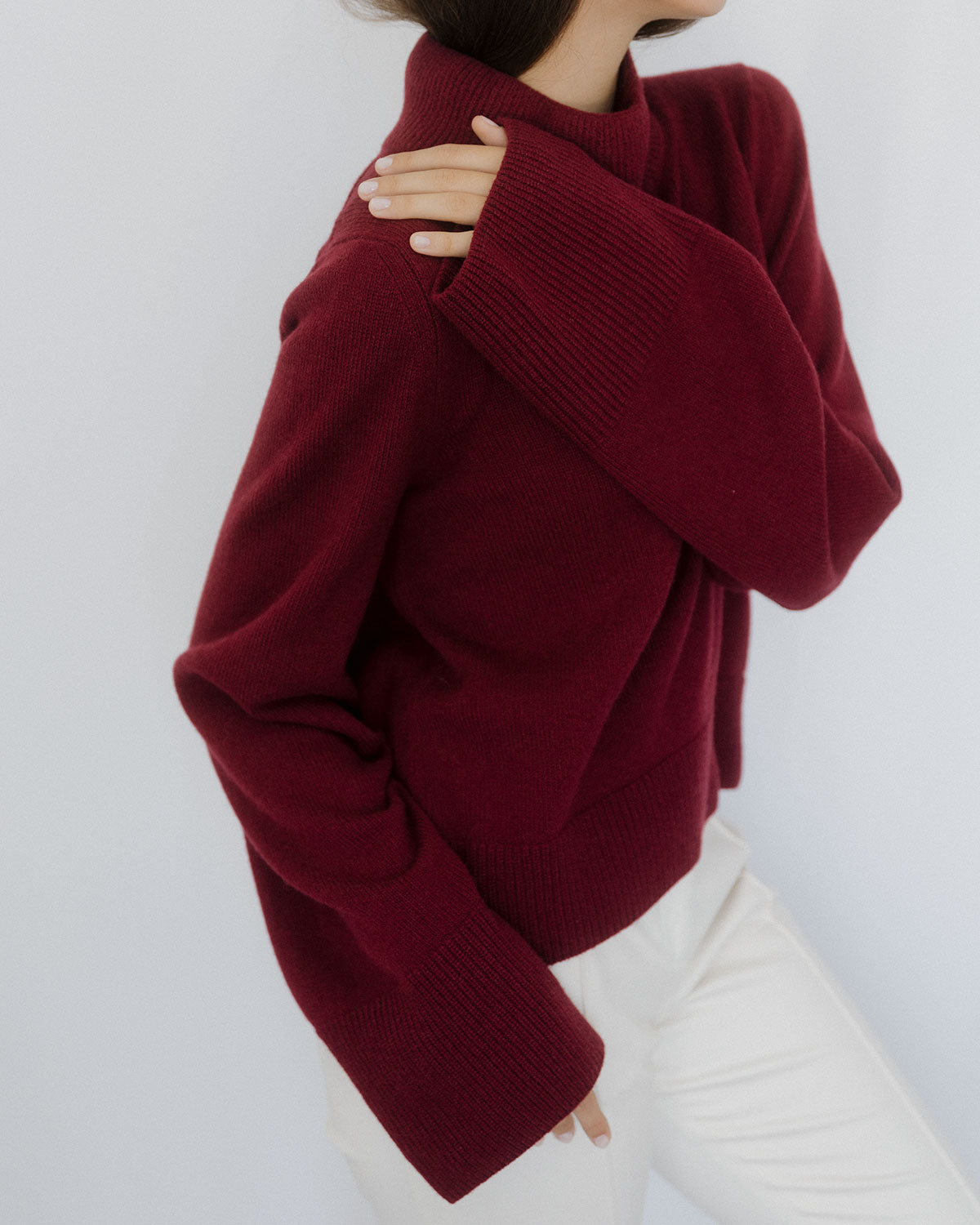 Pull manches larges Nuage Cashmere en Burgundy, porté de face sur un pantalon blanc