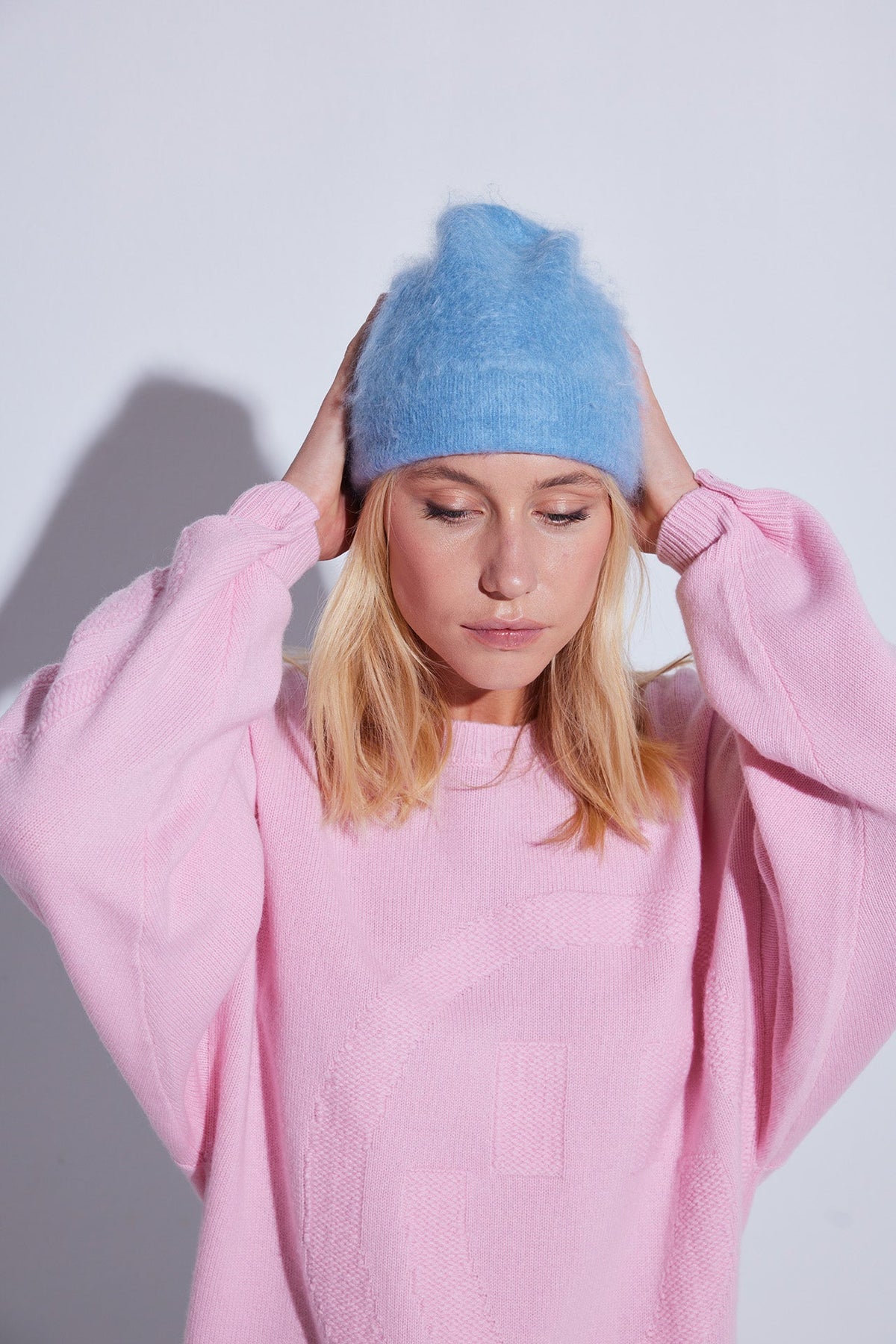 Bonnet brossé Byron COLORUSH en coloris Stonewash, mains posées sur le bonnet, avec un pull rose pâle