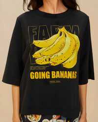 Gros plan sur l'imprimé « Going Bananas » du t-shirt FARM Rio : bouquet de bananes jaunes encadré, texte « GOING BANANAS » et mention « FARM RIO – BRASIL »