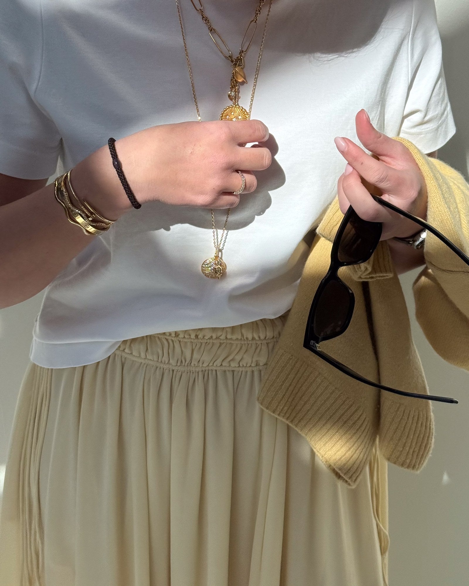 Élastique à cheveux Kknekki noir porté au poignet avec des bracelets dorés
