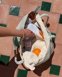 Kknekki Original Taupe Clair porté au poignet, la main sur un sac de plage