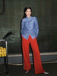 Chemise à rayures LANIUS portée avec un pantalon rouge sur un court de tennis – lifestyle