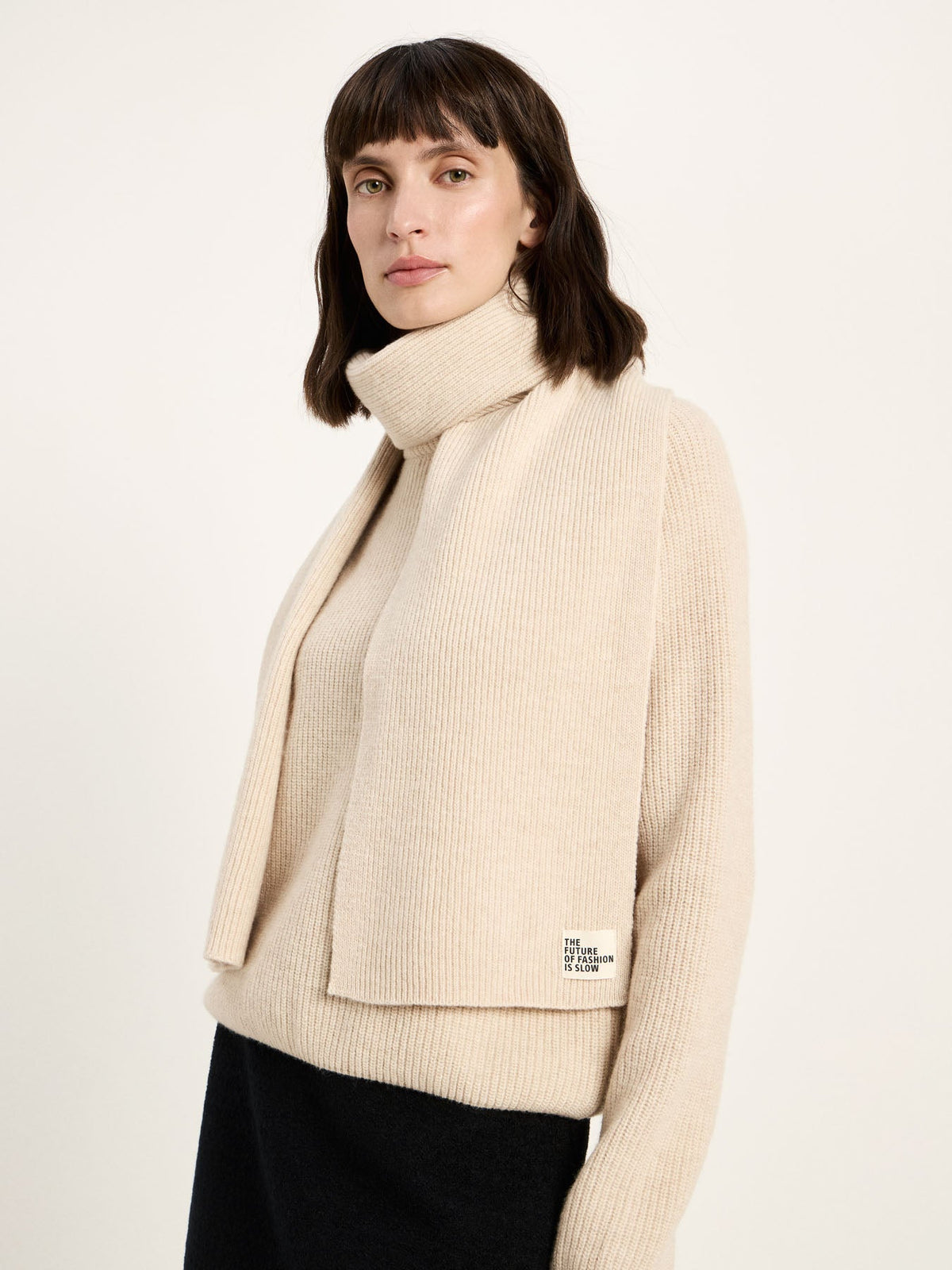 Écharpe côtelée laine et coton bio LANIUS Blanc cassé portée sur une veste crème et un pantalon noir
