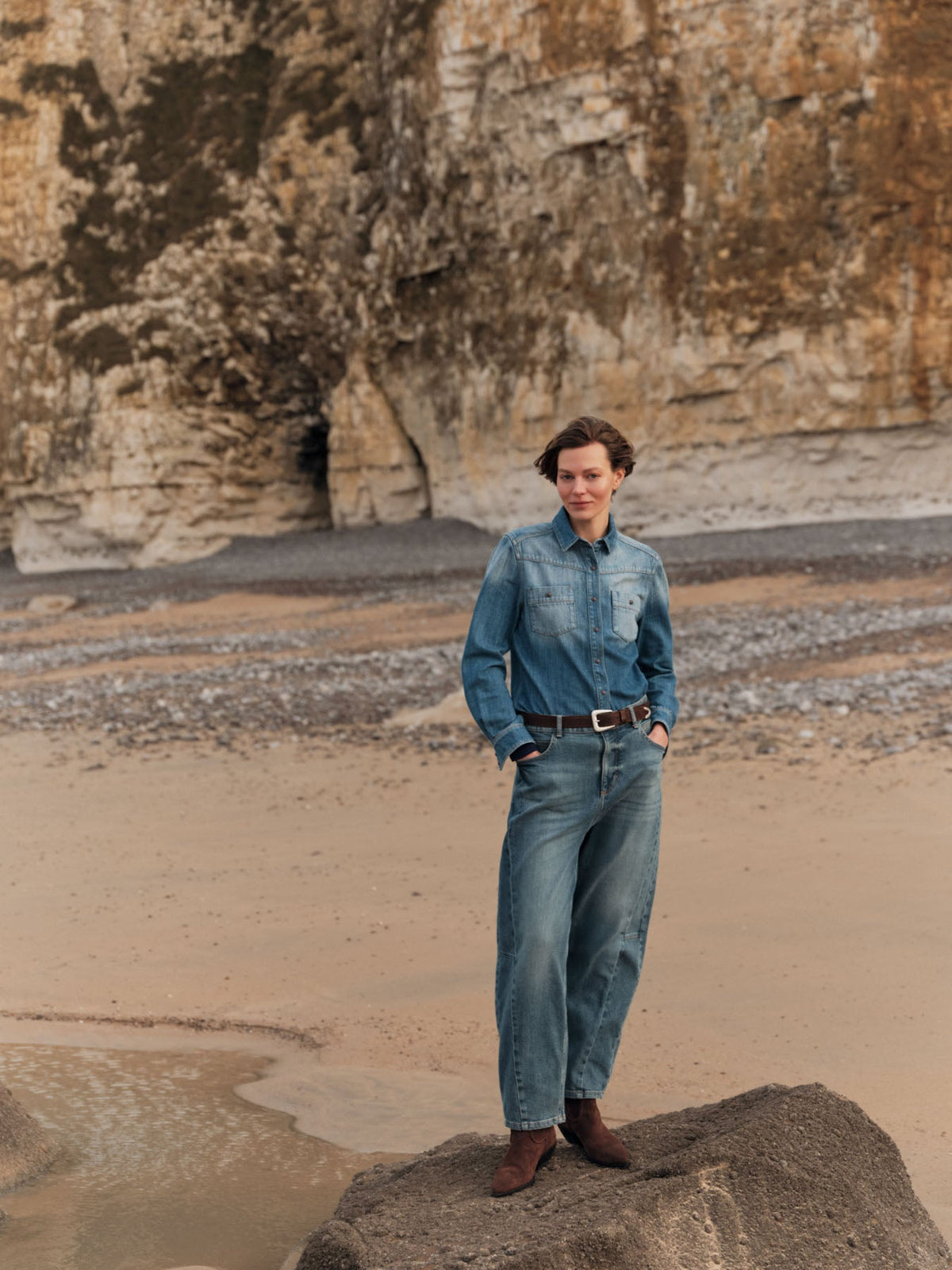 Jean barrel Ember LANIUS Denim bleu moyen porté avec une chemise en jean, sur les rochers d’une plage