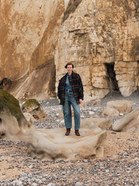 Manteau court à carreaux LANIUS Noir & marron porté sur une plage de galets au pied des falaises
