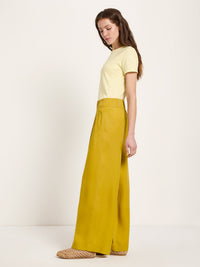 Vue de profil du pantalon large vert kiwi LANIUS porté avec un t-shirt jaune pâle et des sandales tressées