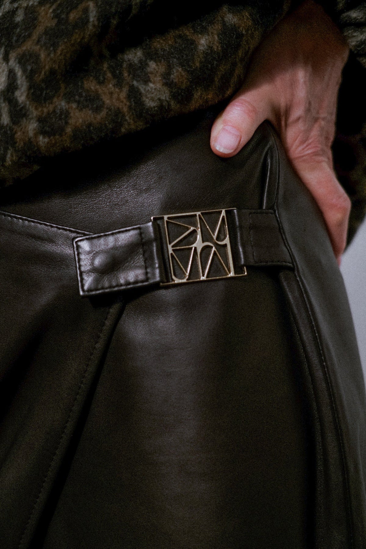 Jupe portefeuille en cuir MOS MOSH noire – détail de la boucle métallique sculptée à la hanche
