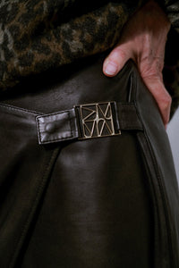 Jupe portefeuille en cuir MOS MOSH noire – détail de la boucle métallique sculptée à la hanche