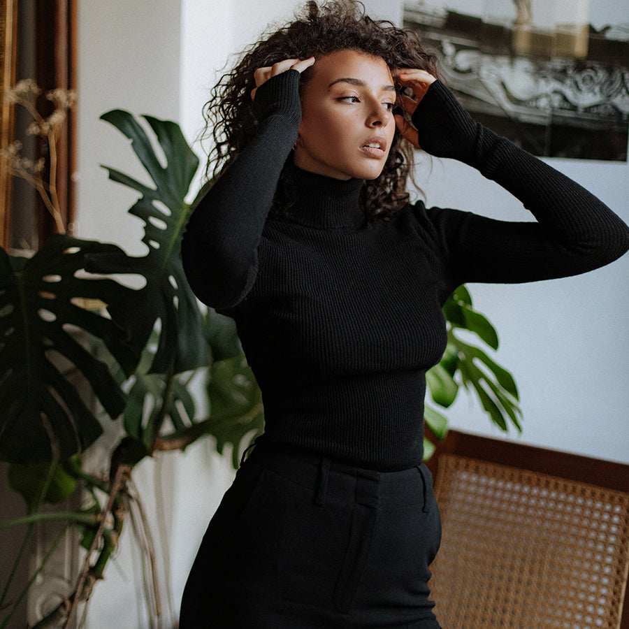 Col roulé fin Nuage Cashmere en noir, porté de trois quarts, bras levés