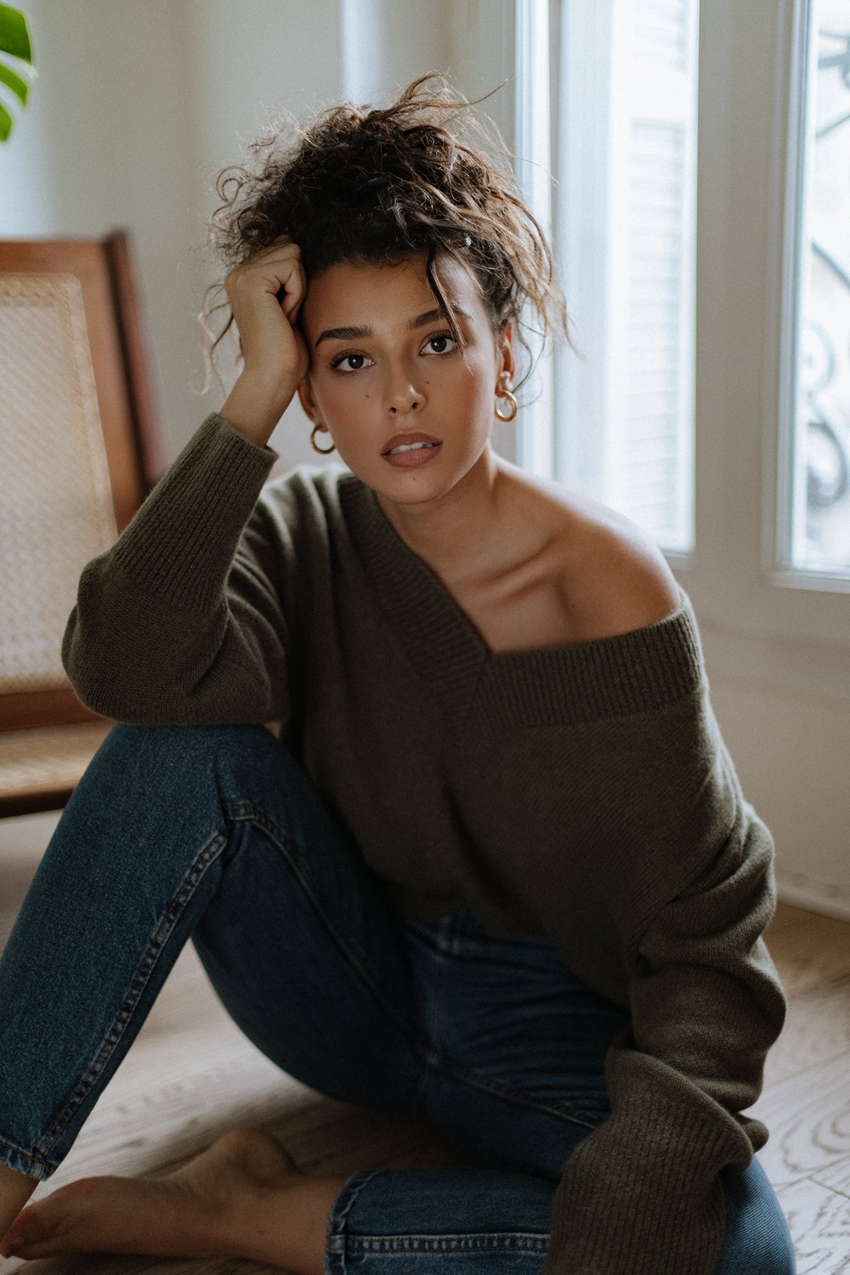 Pull col V Iconic Nuage Cashmere en Olive, porté épaule dénudée avec un jean